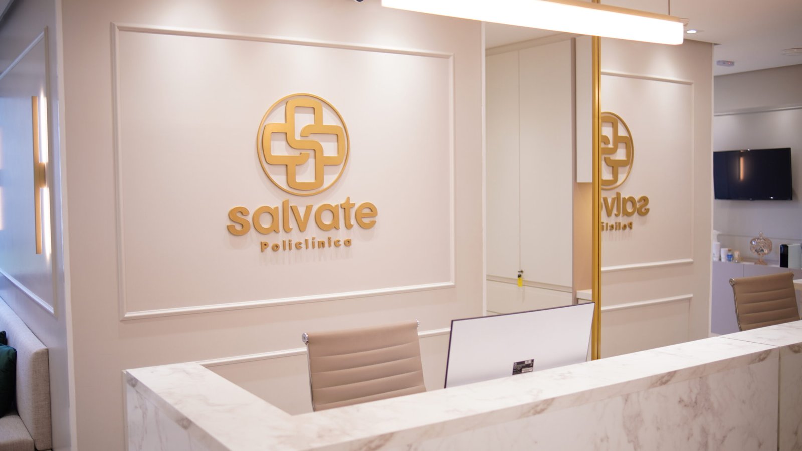 Recepção da Policlínica Salvate com o logo dourado na parede